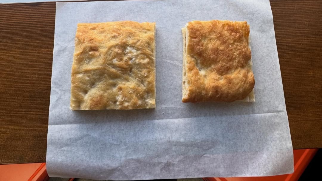 Close-up of schiacciata — golden crust, olive oil glistening, airy interior visible